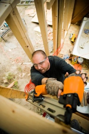Man using a nail gun. Whether you are adding new shingles to a roof or