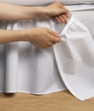 Woman putting a bedskirt on a bed