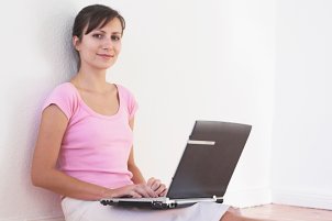 Woman typing on a black widescreen laptop computer