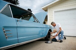 Father and son use automotive tools on a car
