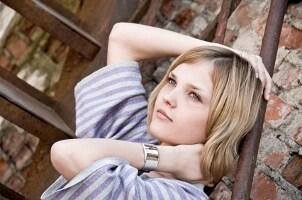 Pretty blond girl on an urban fire escape wearing a Citizen watch and a striped sweater