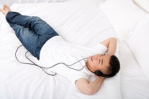 Cute student laying on his mattress and listening to music