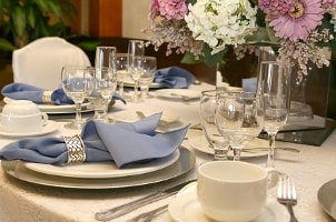 Elegant formal table setting with blue napkins and centerpiece of real flowers