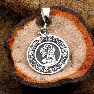 A silver pendant with an Aztec design