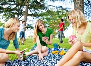 Three women play cards at a picnic
