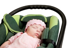 Adorable baby girl sleeping in a green car seat