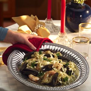 Woman serves seafood pasta in Wilton Armetale bowl