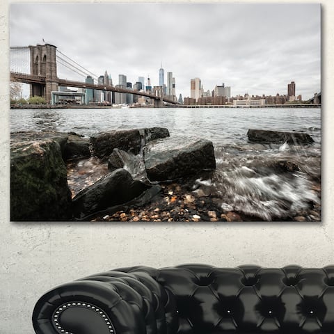 Designart 'Brooklyn Bridge with Rocks on Shore' Large Cityscape Artwork Print on Canvas - White