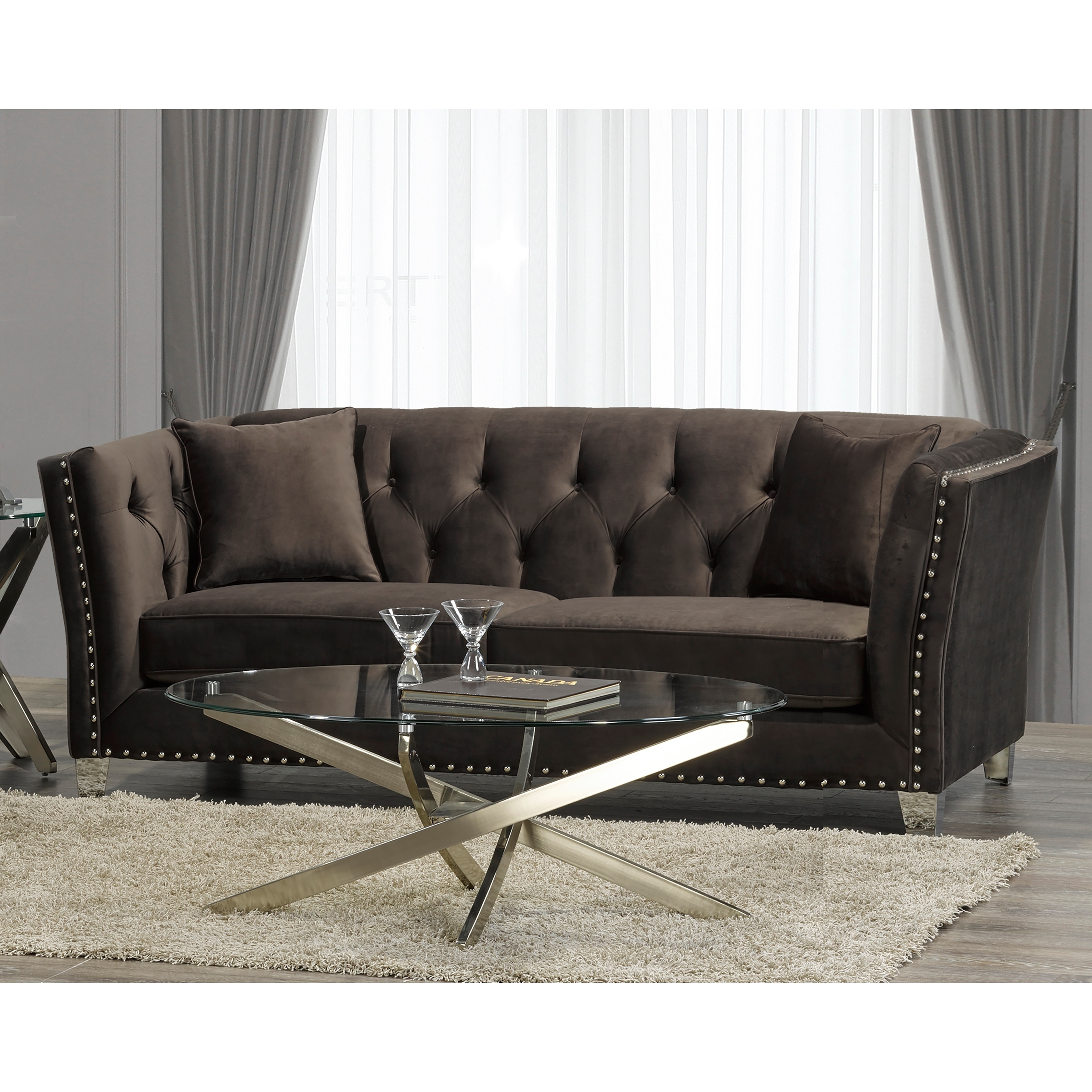 Chocolate brown velvet tufted sofa with a glass coffee table in a living room.