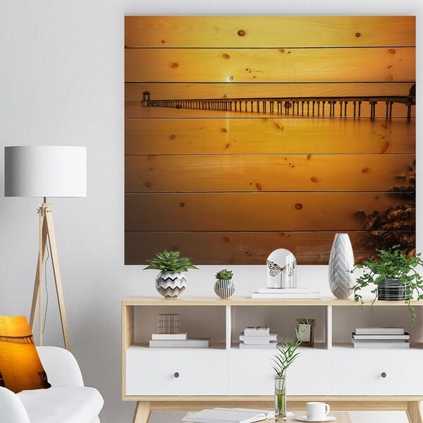Designart 'Yellow Tinged Seashore and Long Pier' Pier Seascape Print on Natural Pine Wood - Orange