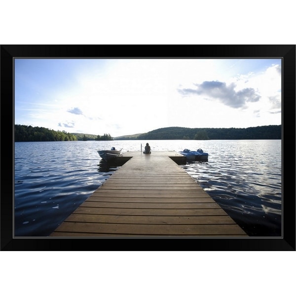 "Person sitting on dock with two boats in water" Black Framed Print