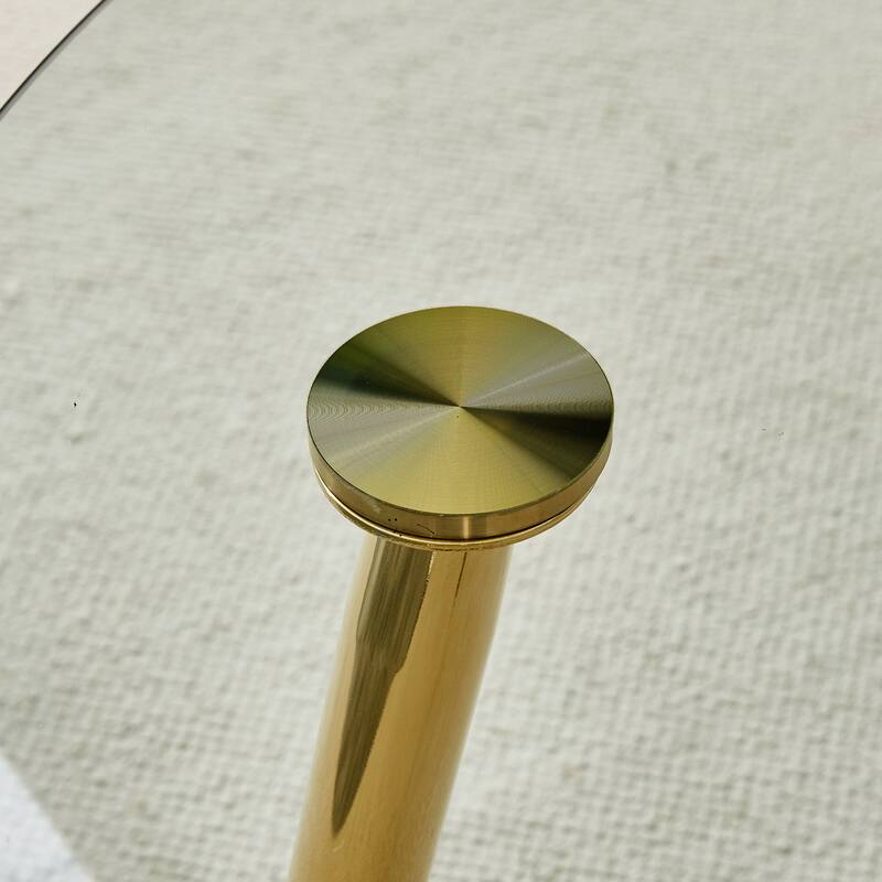 A glass tabletop with a diameter of 40 inches and a modern minimalist circular dining table with gold plated metal legs.