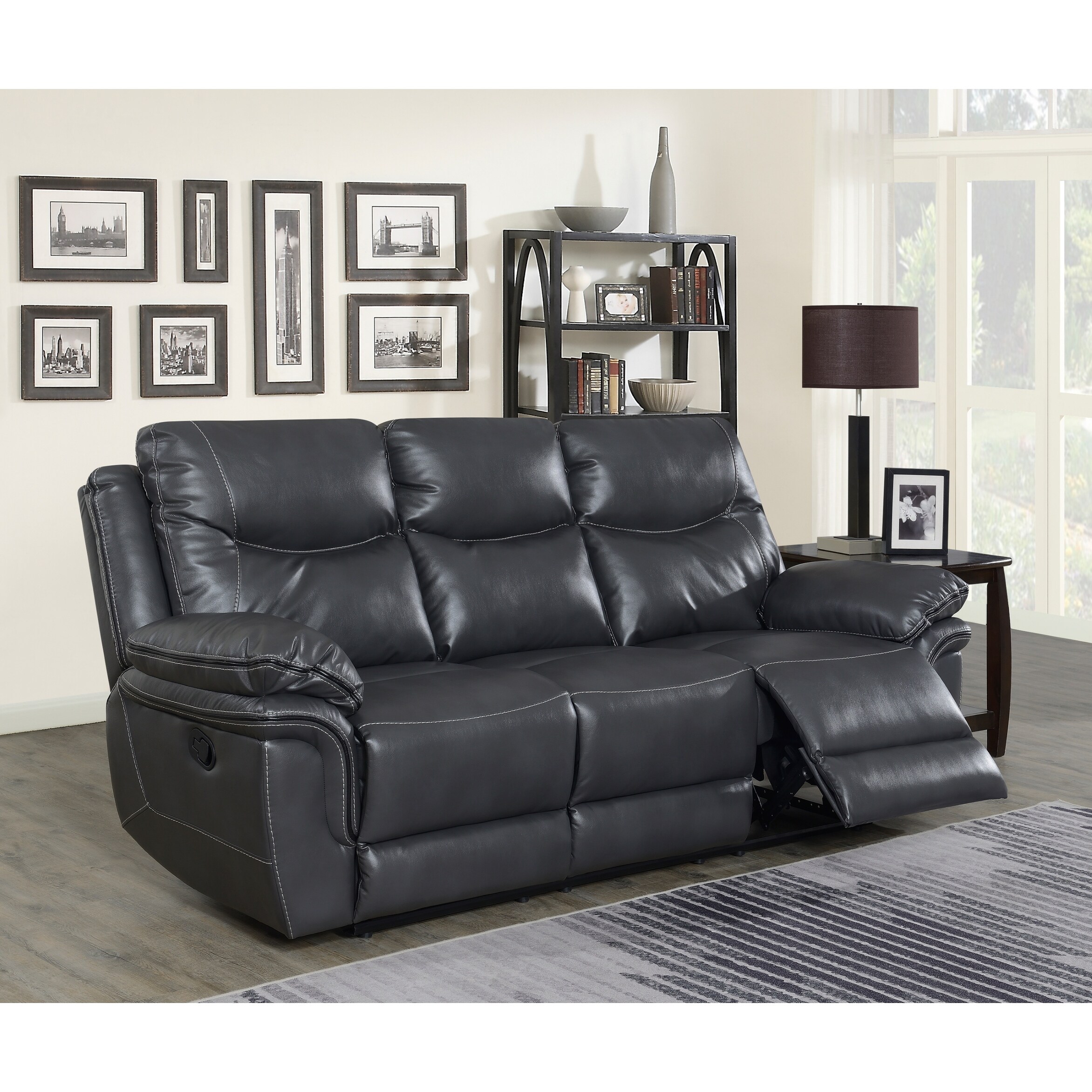 Dark gray leather reclining sofa with two armrests and a footrest extended on the right side