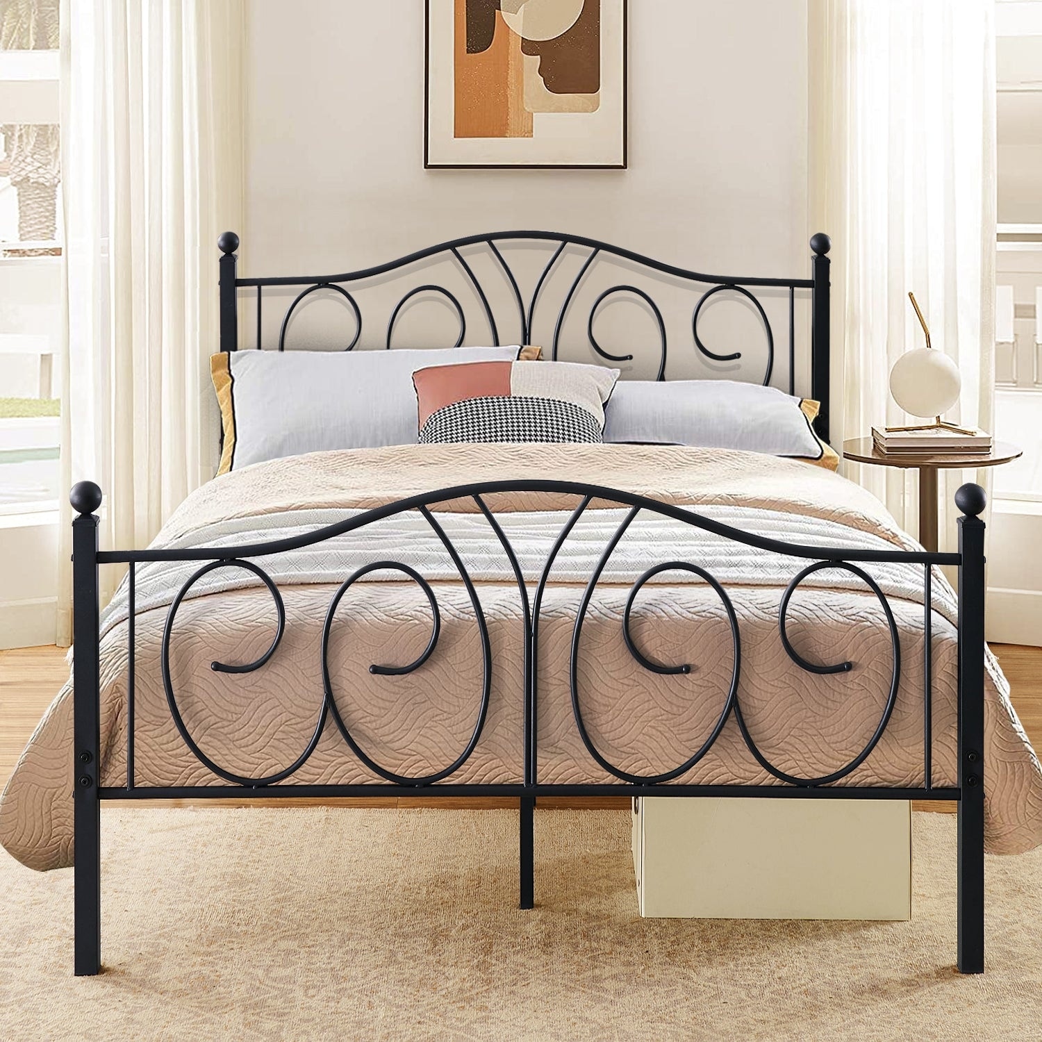 A black metal bed frame with ornate swirl patterns in a bright white bedroom with framed botanical prints above the headboard