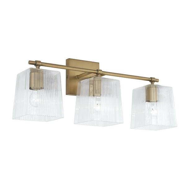 slide 2 of 16, Lexi 3-light 23-inch Bath/ Vanity Fixture w/ Clear Fluted Square Glass Aged Brass