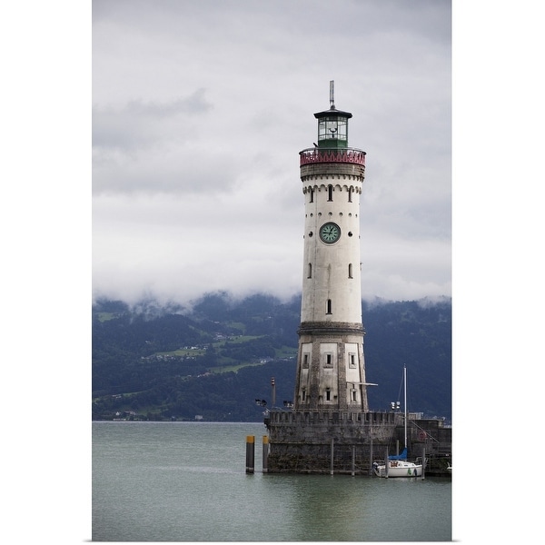 "old lighthouse on a pier of a lake with cloud covered mountains in the background" Poster Print