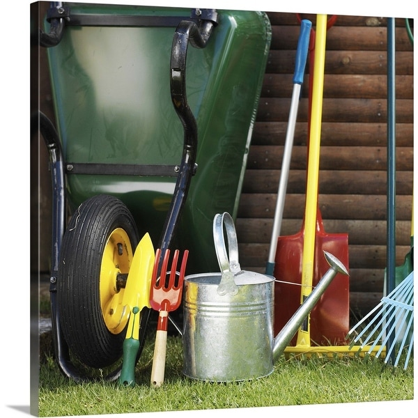 "Array of gardening tools beside a wheelbarrow in a yard" Canvas Wall Art