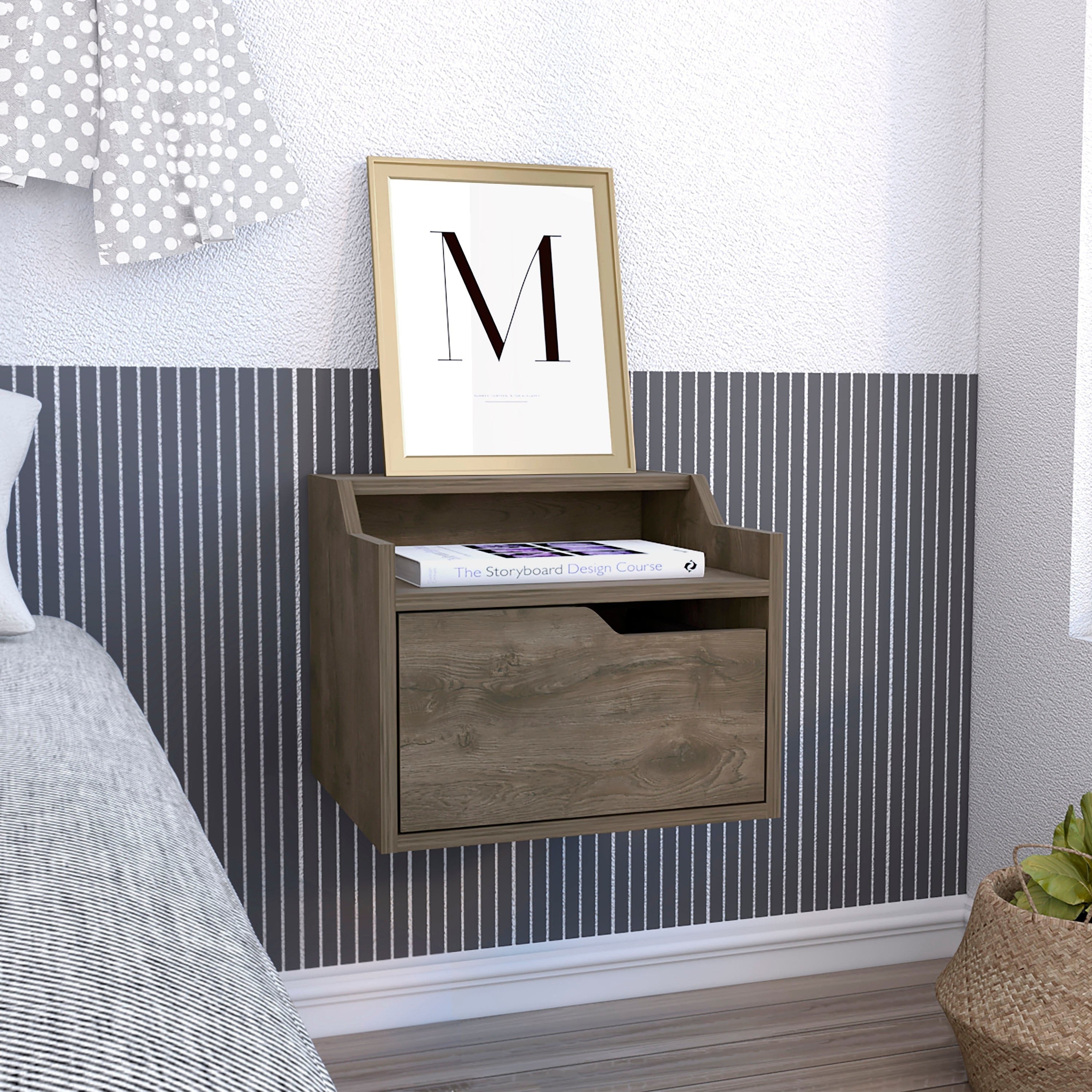 Wooden wall-mounted bedside shelf with top ledge and a file drawer, holding a book and a framed print on top.