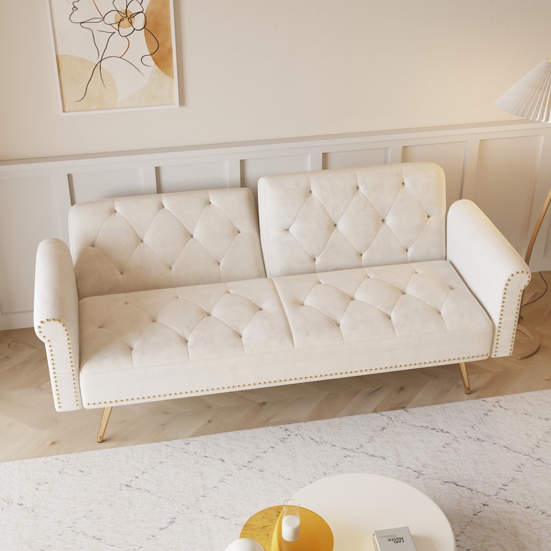 A 69.7-inch-long sofa bed covered in beige velvet fabric, featuring nail head trim and accompanied by a matching throw pillow