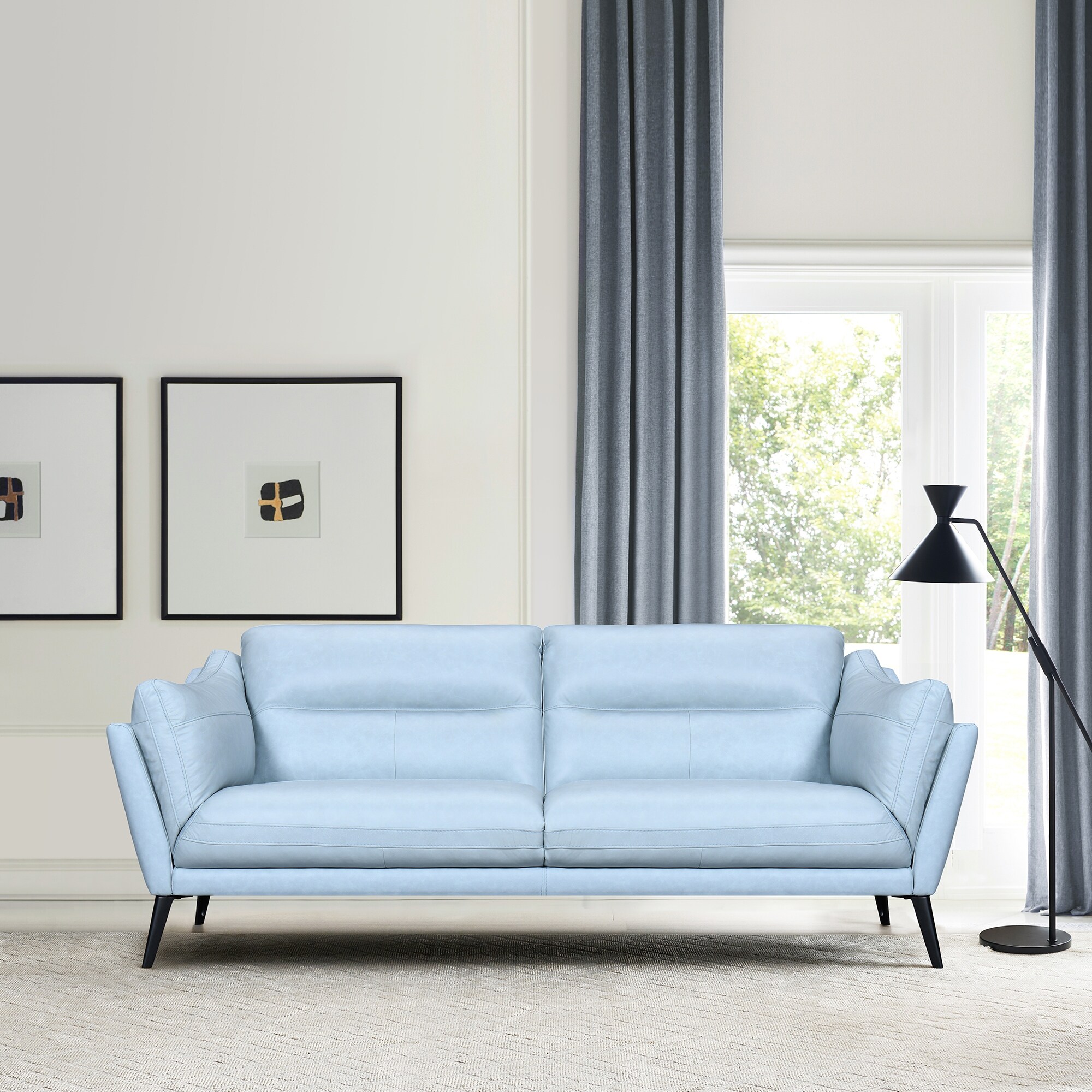 Light gray/blue sofa in living room with curtains and floor lamp.