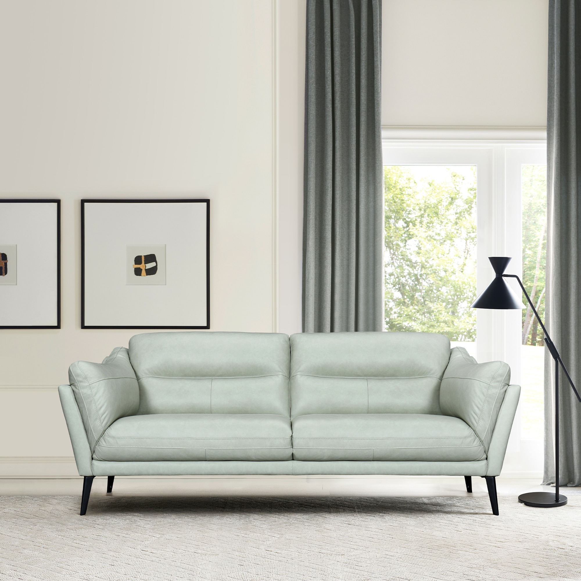 Dark blue leather sofa with angled arms and metal legs against white wall.