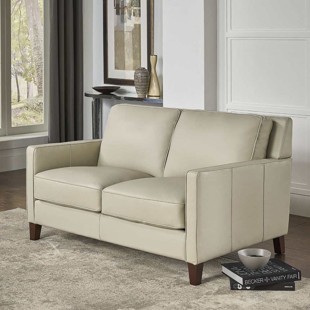A gray leather loveseat sofa with plush cushions and wooden legs in a modern living room.