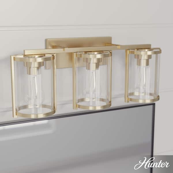 slide 2 of 12, Hunter Astwood Bathroom Vanity Light, Clear Cylinder Glass, Damp Rated, Caged - Contemporary, Transitional, Art-Deco 3-Light 24" - Alturas Gold