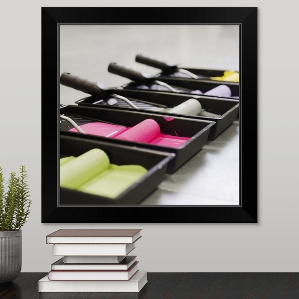 "Close-up side view of trays of coloured paint and paint rollers" Black Framed Print
