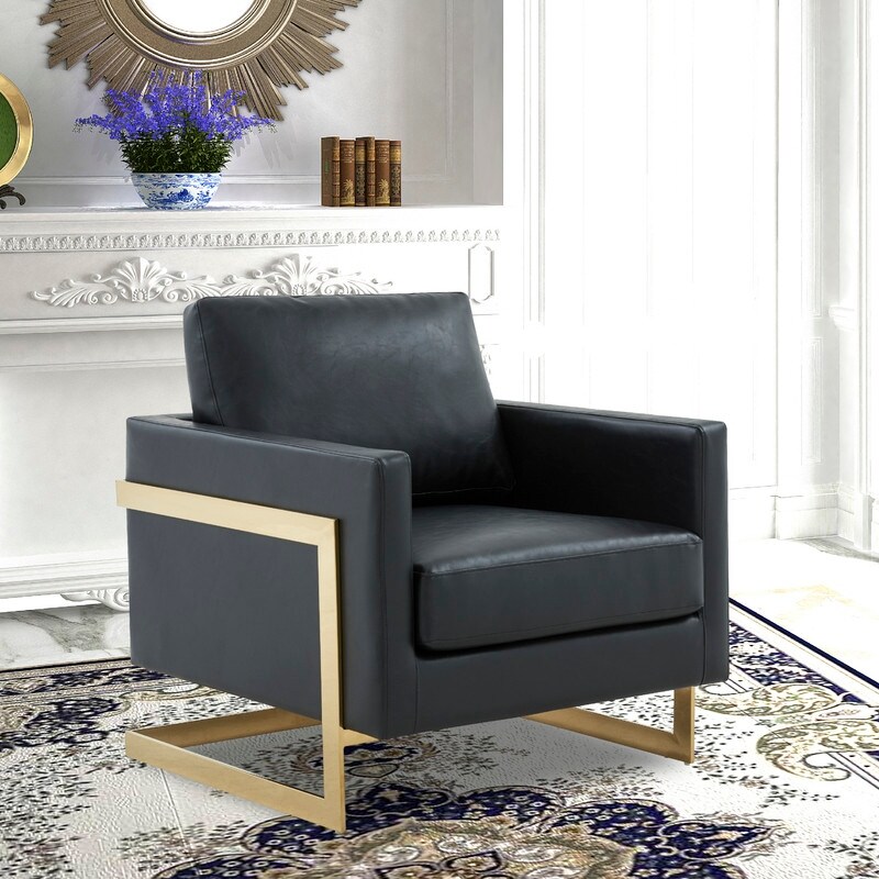 Wide shot of a living room with gray leather chairs and a white ornate wall; a black floor lamp and gold-framed chairs.