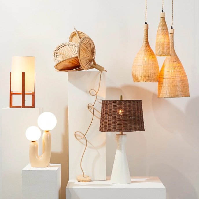 Tiered lighting display showing a variety of lamps with natural shapes and elements and hanging pendant lights with woven wicker shades.