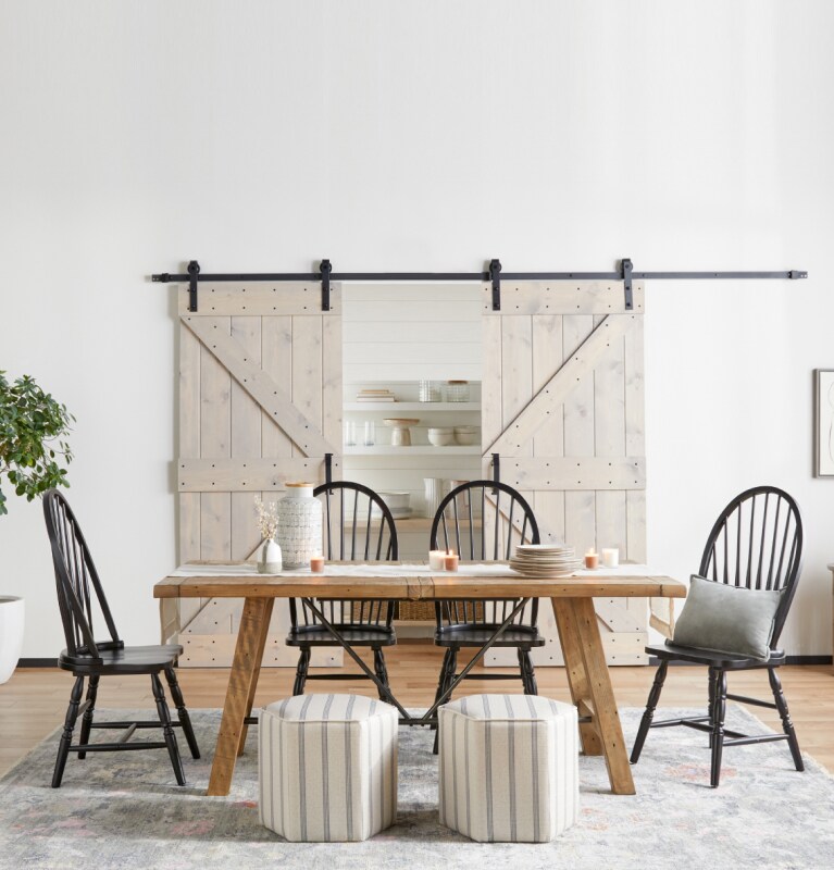 A wooden dining tables surrounded by black wooden chairs and a pair of upholstered cube seats available online at Overstock