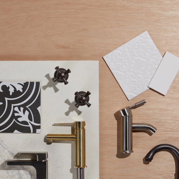 An overhead display of black and white bathroom tile samples, black cross handles, and four different bathroom faucets.