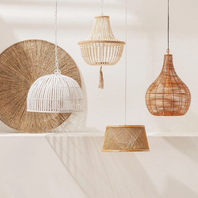 A row of hanging pendant lights including a white wicker dome light, a beaded chandelier, a woven seagrass bell light, and a wicker gourd light. 