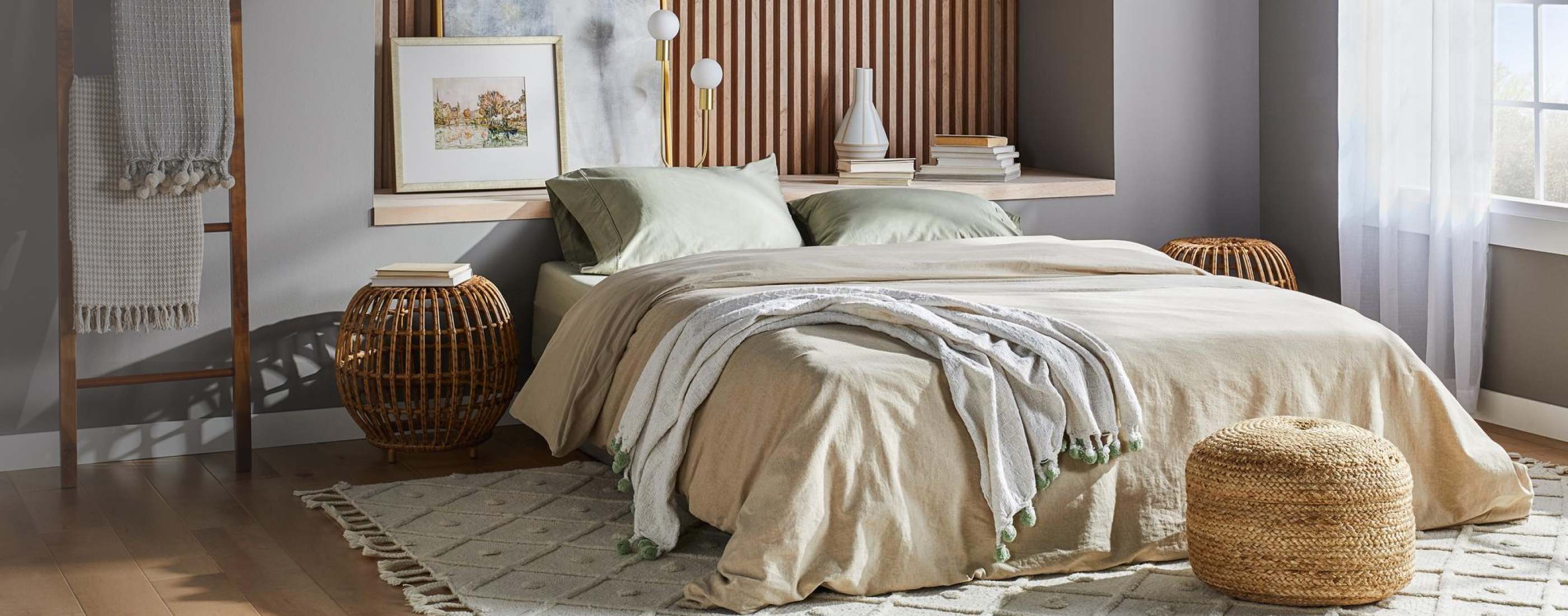 A bedroom with a low, king size bed and beige bedding, with natural materials and other accents.