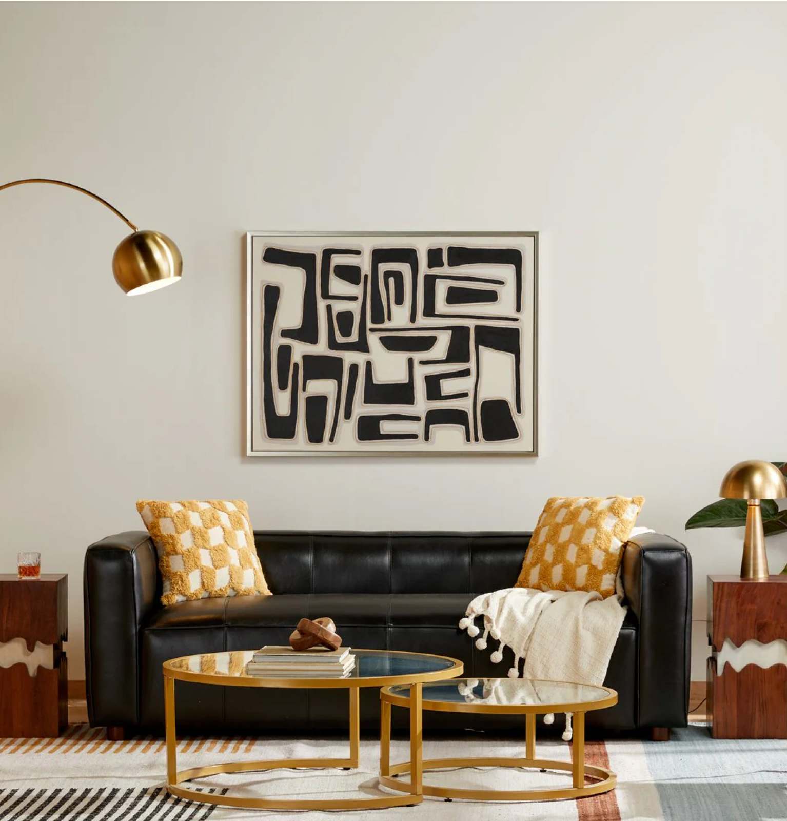 A modern living room with a black leather sofa and yellow throw pillows that are available online at Overstock.
