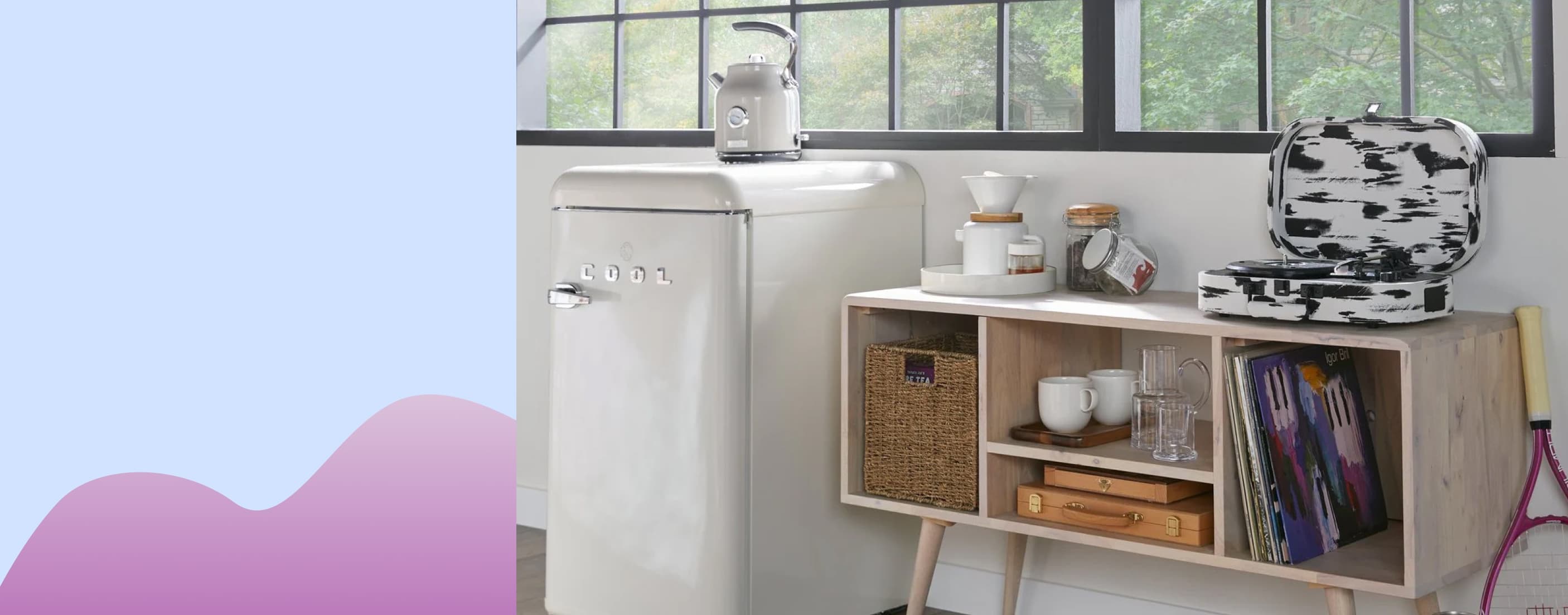 A white mini-fridge is shown with a coffee pot on top. Next to the fridge is a mid-century modern wooden console table with separated cabinets filled with books, dishes, and other supplies.
