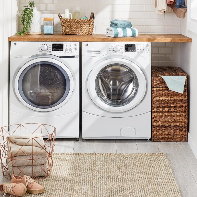a washer and dryer in a white laundry room with baskets and folded linen for sale at overstock