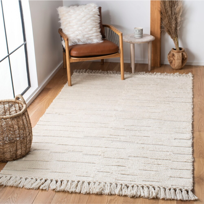 A display of neutral-tone area rugs, overlapping to show off their patterns in a room with beige curtains. 
