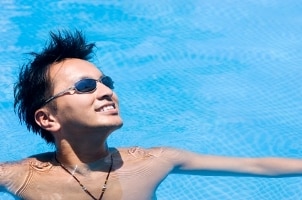 Cute Asian guy wearing a leather necklace in a blue swimming pool