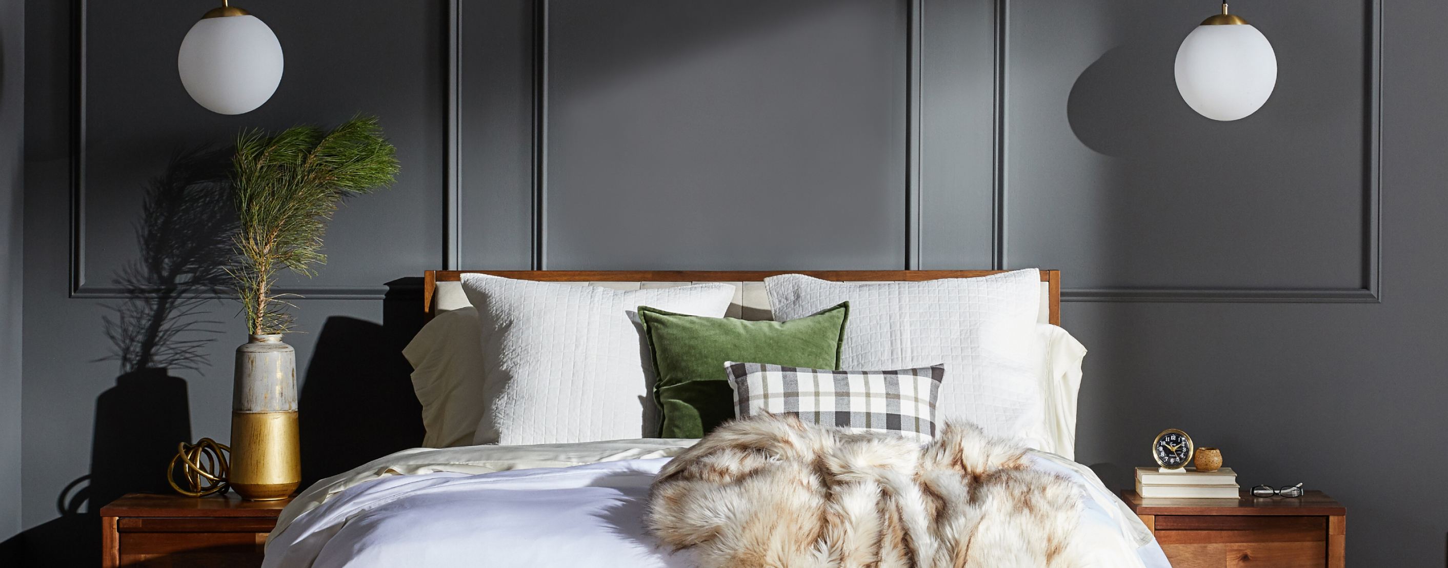 a holiday themed bedroom with a faux-fur throw on a sumptuous bed with pine green accent pillows available online at Overstock