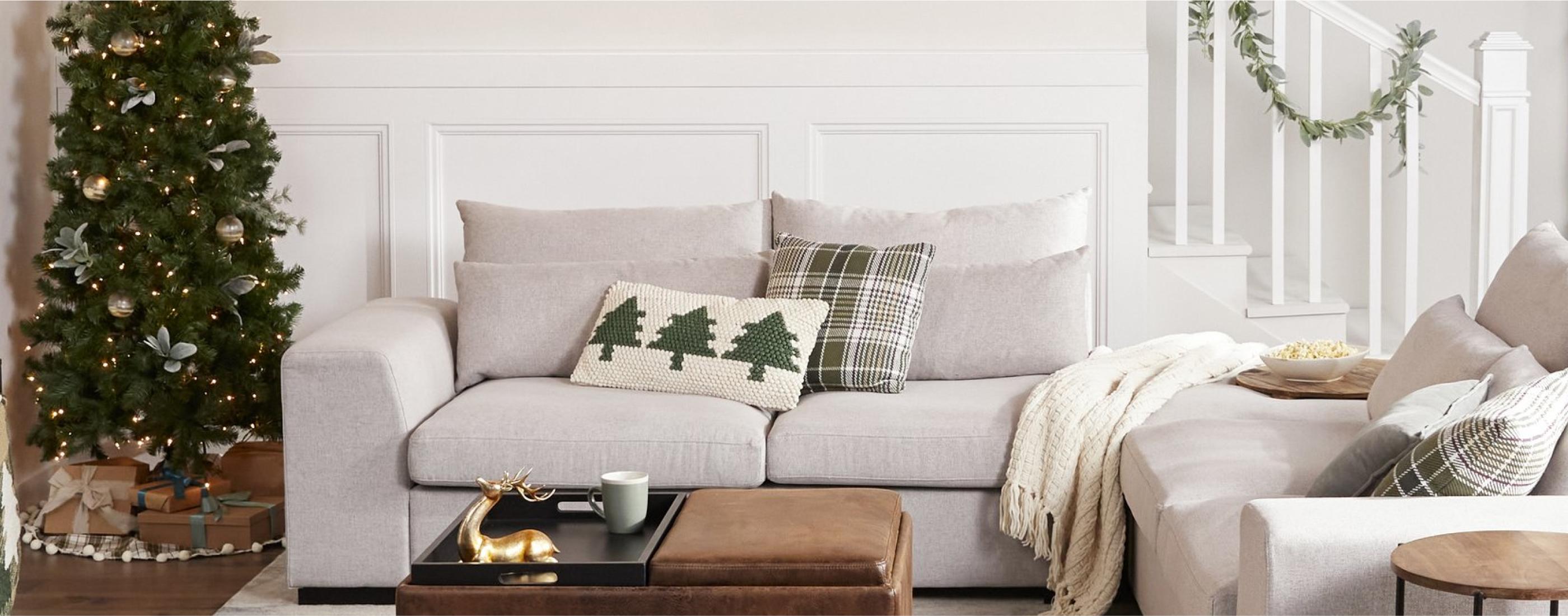 a living room decorated for christmas with holiday throw pillows on a sofa and a large christmas tree available online at Overstock