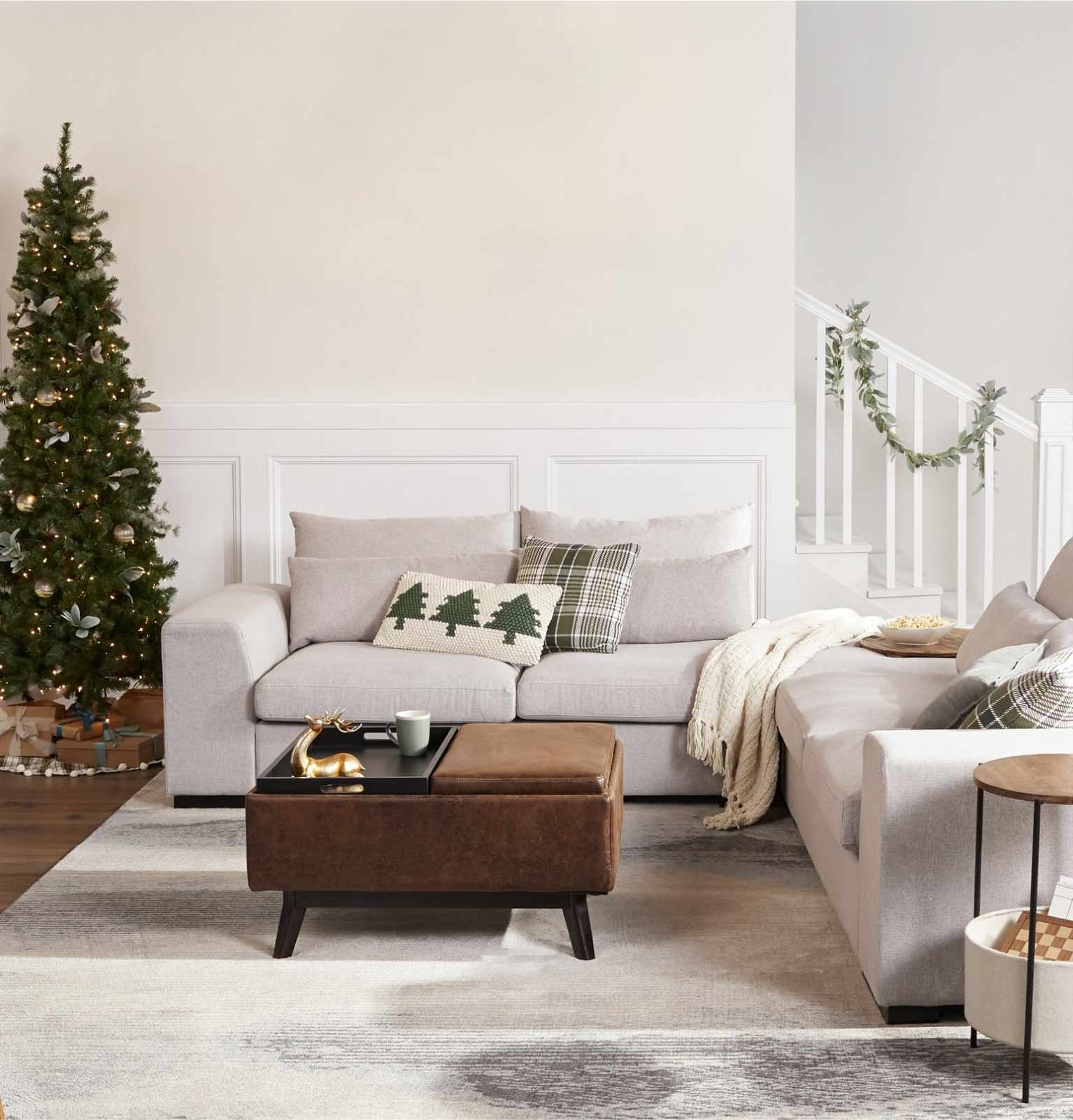 a living room decorated for christmas with holiday throw pillows on a sofa and a large christmas tree available online at Overstock