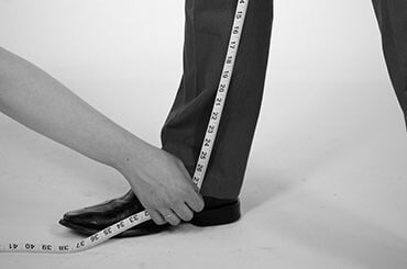 Man in dress clothes having his inseam measured