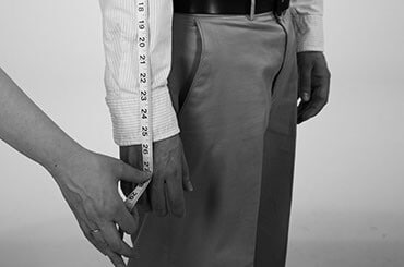 Side view of man in dress clothes having his sleeve measured
