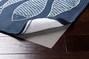 Prevent Falling Accidents Blue rug with fish design pulled back to expose rug pad beneath