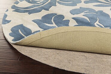 What's the Right Rug Pad for You? Blue and cream round floral rug pulled back to expose rug pad beneath
