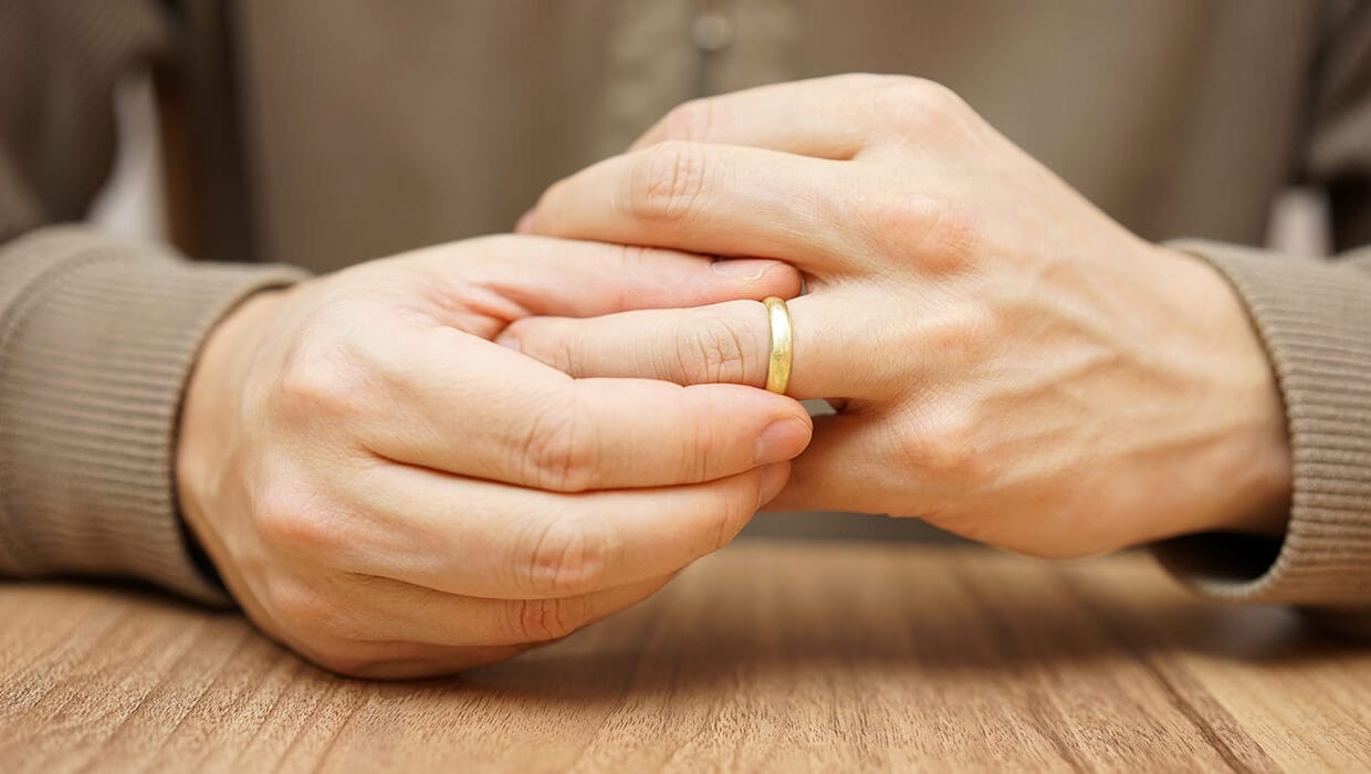 Close up of guys hand putting on his wedding ring