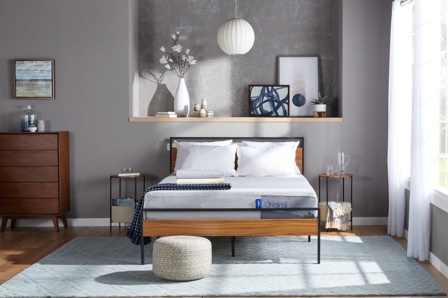 A mattress on a wooden bedframe in a room with grey walls