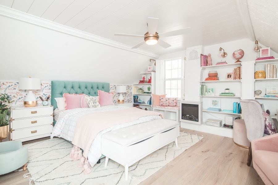 Bedroom with pink and white bedding, a blue headboard, and a fan