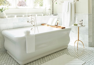 White porcelain tub beside a small table and a white rug